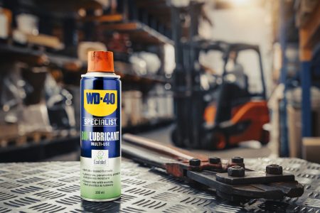 WD-40 Specialist Bio-Schmierspray Dose auf Riffelblech in einer Industriewerkstatt, daneben ein Bolzenschneider, im unscharfen Hintergrund ein Gabelstapler