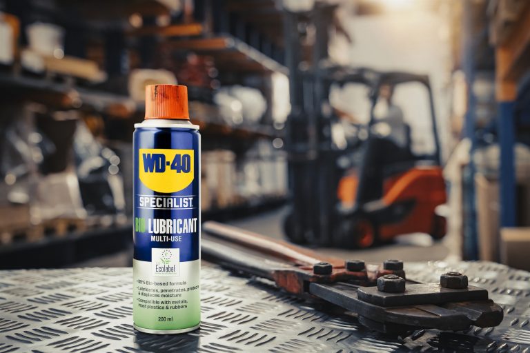 WD-40 Specialist Bio-Schmierspray Dose auf Riffelblech in einer Industriewerkstatt, daneben ein Bolzenschneider, im unscharfen Hintergrund ein Gabelstapler