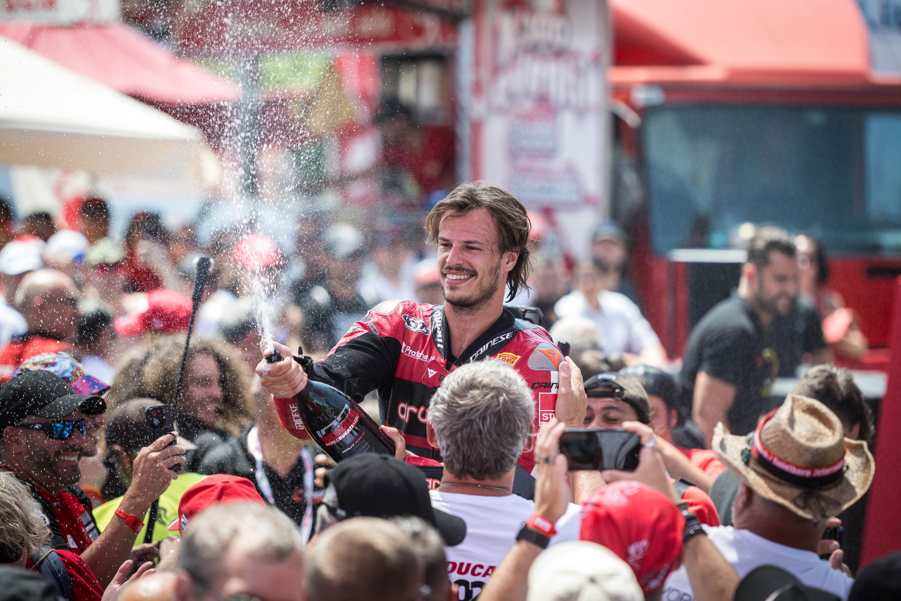 World Ducati Week 2026: 118.036 Fans feiern Ducatis 100. Geburtstag 6 Fahrer wird beim Feiern in der Menge mit Champagner bespritzt bei der World Ducati Week 2026 in Misano