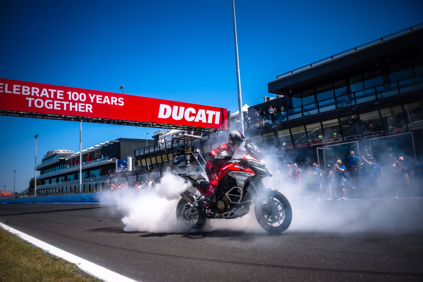 World Ducati Week 2026: 118.036 Fans feiern Ducatis 100. Geburtstag 7 Ducati-Fahrer mit qualmendem Burnout unter dem Celebrate-100-Years-Together-Tor in Misano