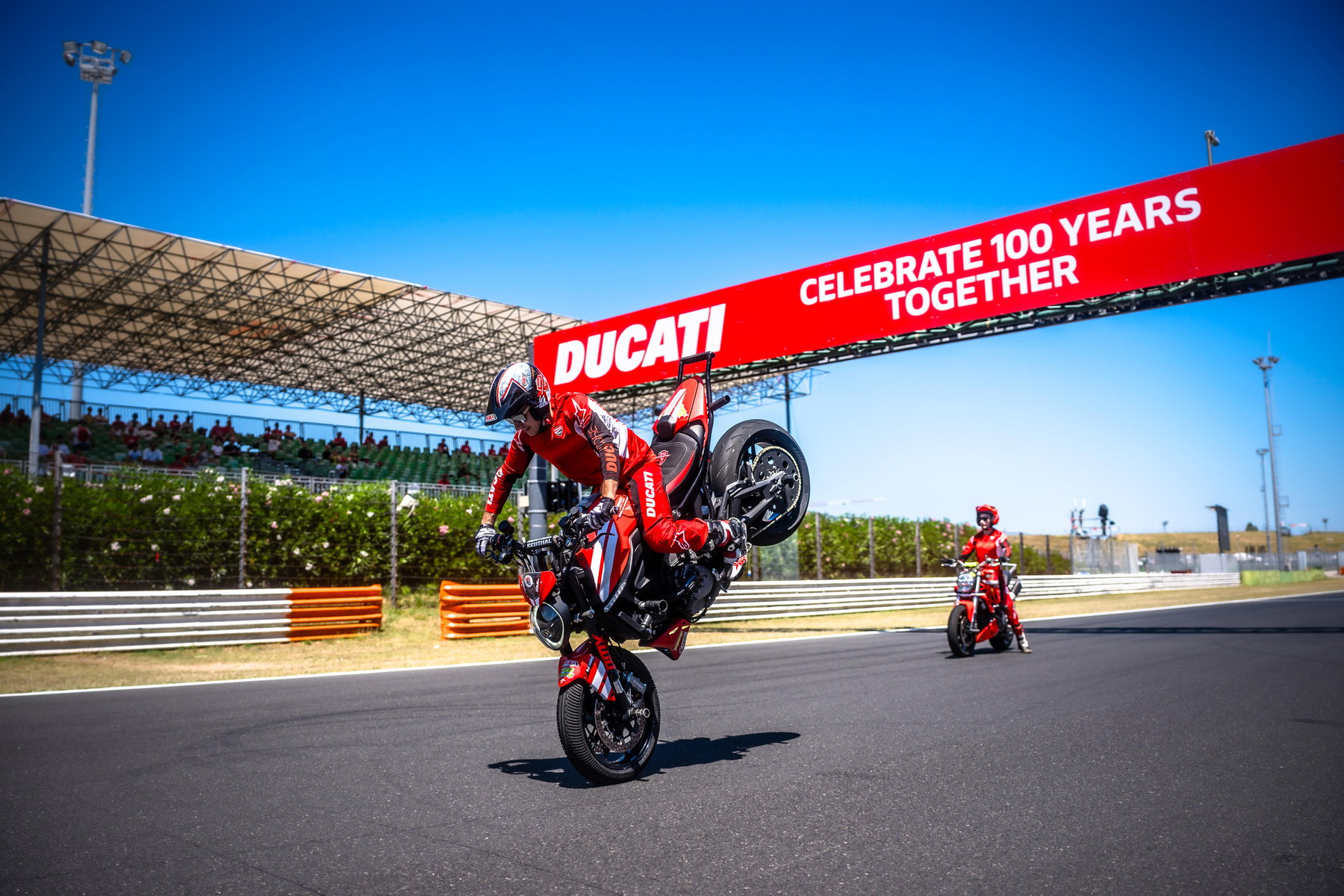 World Ducati Week 2026: 118.036 Fans feiern Ducatis 100. Geburtstag 5 Fahrer im Wheelie unter dem Ducati-Torbogen Celebrate 100 Years Together auf der Strecke in Misano