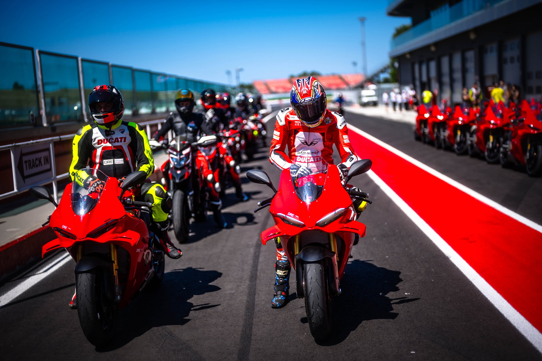 Ducati-Werksfahrer in roten Lederkombis auf ihren Motorrädern in der Boxengasse der World Ducati Week 2026