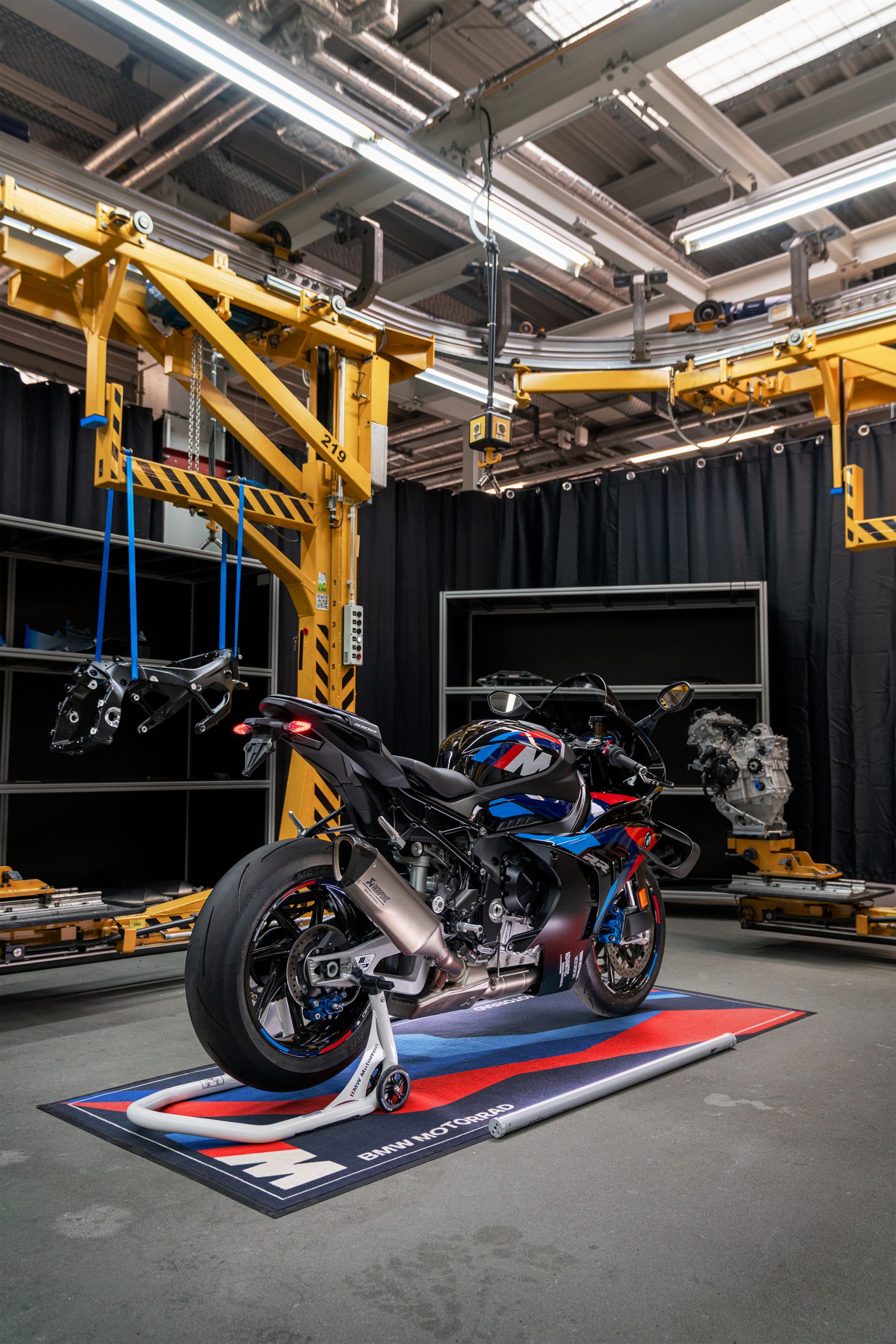 BMW M 1000 RS: Erstes RS-Modell mit Vierzylinder rückt näher 8 BMW M 1000 RR 2027 in M Motorsport Lackierung – Heckansicht auf BMW M Teppich in der Montagehalle, dahinter der neue M Motorsport Rahmen