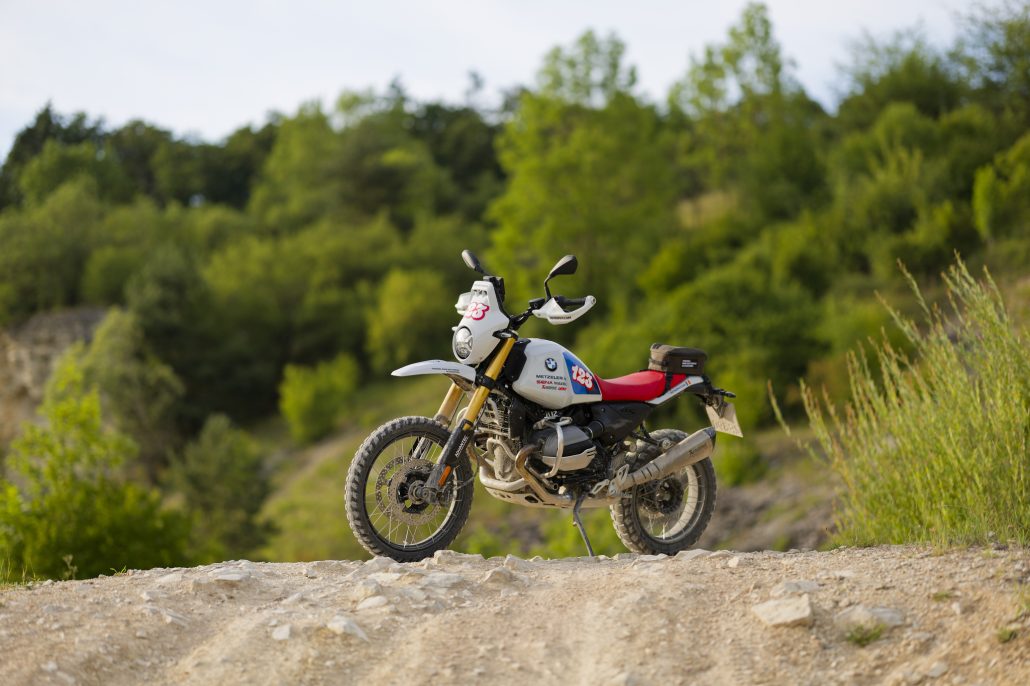 BMW R 12 G/S GS Trophy Competition Bike 2026 – Seitenansicht von links mit blauen Tank-Tapes und roter Sitzbank auf Geländekuppe