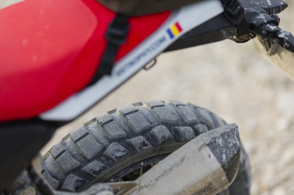 BMW R 12 G/S GS Trophy Competition Bike 2026 – Detail des Hinterrads mit Geländereifen, roter Sitzbank und Rumänien-Flagge