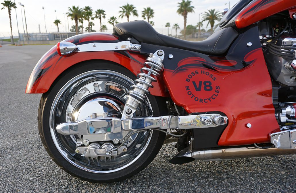 Boss Hoss Cruiser 2026: 8,1-Liter-V8 mit 600 PS im Einstiegsmodell 4 Boss Hoss Cruiser 2026 – Detailansicht von Hinterrad und Sitzbank des rot-schwarzen V8-Choppers vor Palmenkulisse