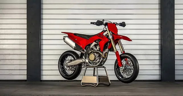 Ducati Desmo450 SM 2026 – rote Studioaufnahme in 3/4-Seitenansicht vor Rolltor, mit Aluminium-Endschalldämpfer und Ducati-450-Desmo-SM-Schriftzug am Heck