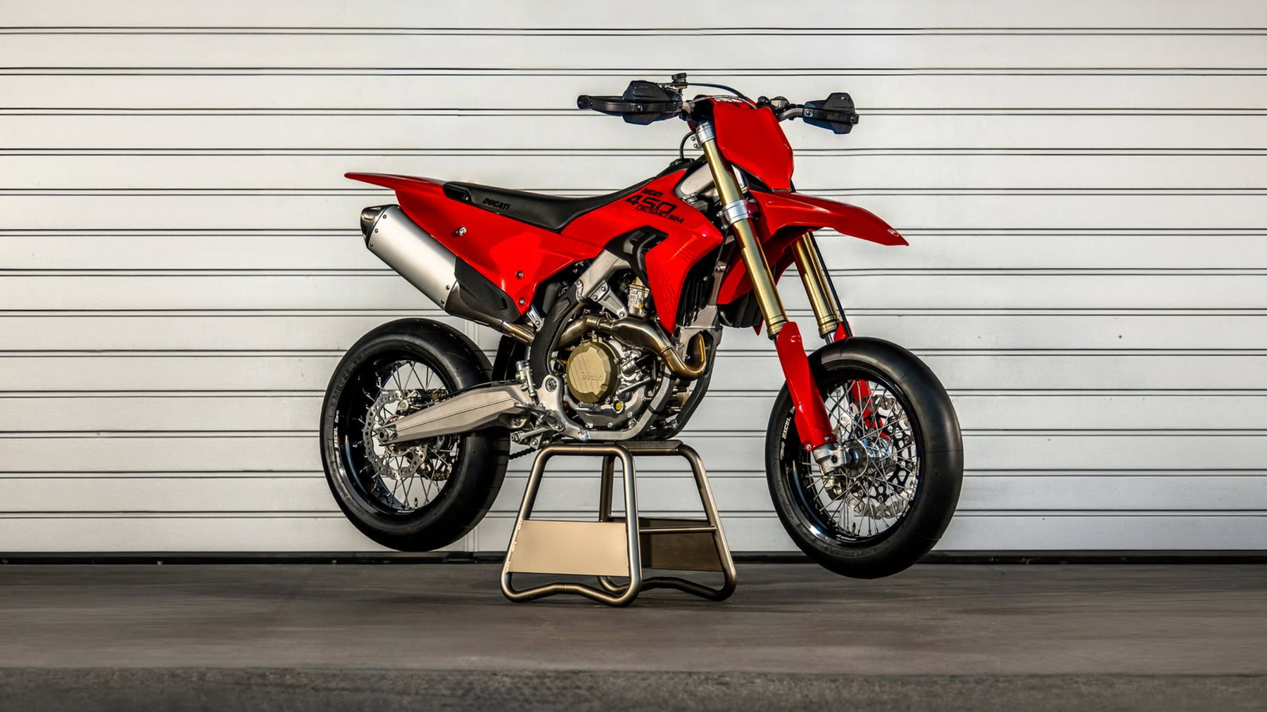 Ducati Desmo450 SM: Erste Renn-Supermoto der Marke feiert Premiere 1 Ducati Desmo450 SM 2026 – rote 3/4-Ansicht im Fahrerlager der World Ducati Week 2026 mit weiteren Ducati-Renntransportern im Hintergrund