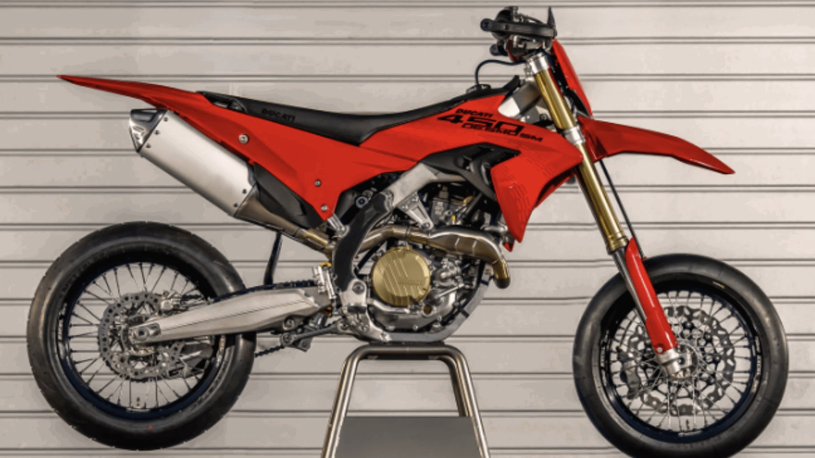 Ducati Desmo450 SM: Erste Renn-Supermoto der Marke feiert Premiere 4 Ducati Desmo450 SM 2026 – rote Studio-Seitenansicht freigestellt vor Rolltor, zeigt Supermoto-Silhouette mit hochgezogenem Heckkotflügel