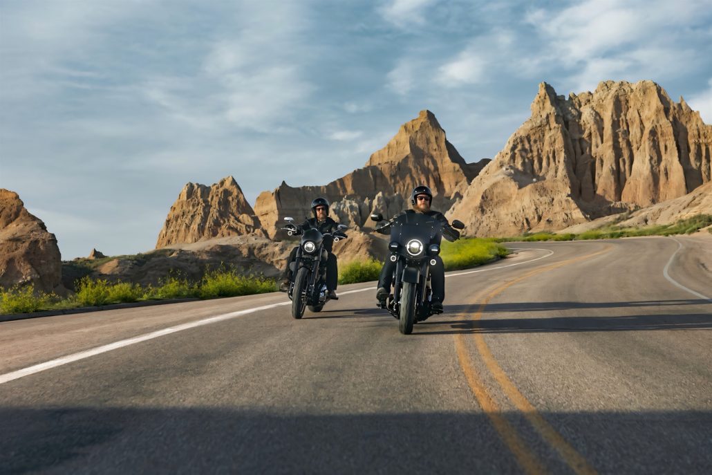 Harley-Davidson Deadwood: Werks-Bobber kommt nicht nach Europa 1 Harley-Davidson Deadwood – zwei Fahrer auf mattschwarzen Cruisern auf kurviger Landstraße durch die Felsformationen der Badlands