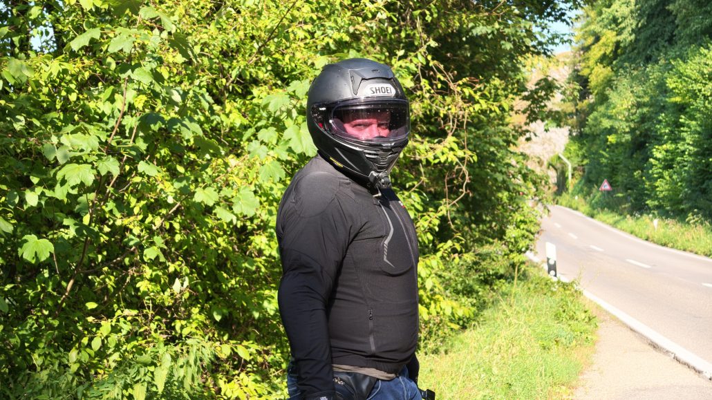 Kemimoto Motorradjacke 2026 – Fahrer im Profil am Rand einer Landstraße, körpernaher Schnitt und Schulterprotektor erkennbar