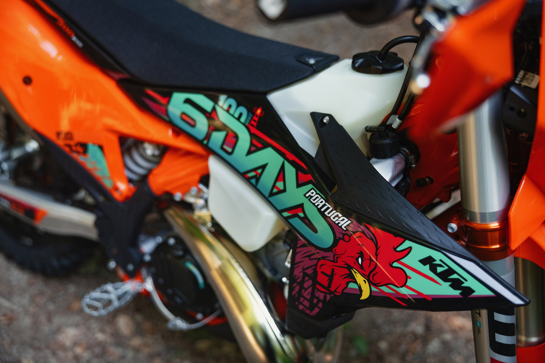 KTM EXC 6DAYS 2027: Special Edition for the 100th Six Days in Portugal 3 KTM 300 EXC 6DAYS 2027 – Detailansicht von Kühlerspoiler und 6DAYS-Portugal-Grafik mit sichtbarer Zweitakt-Auspuffanlage