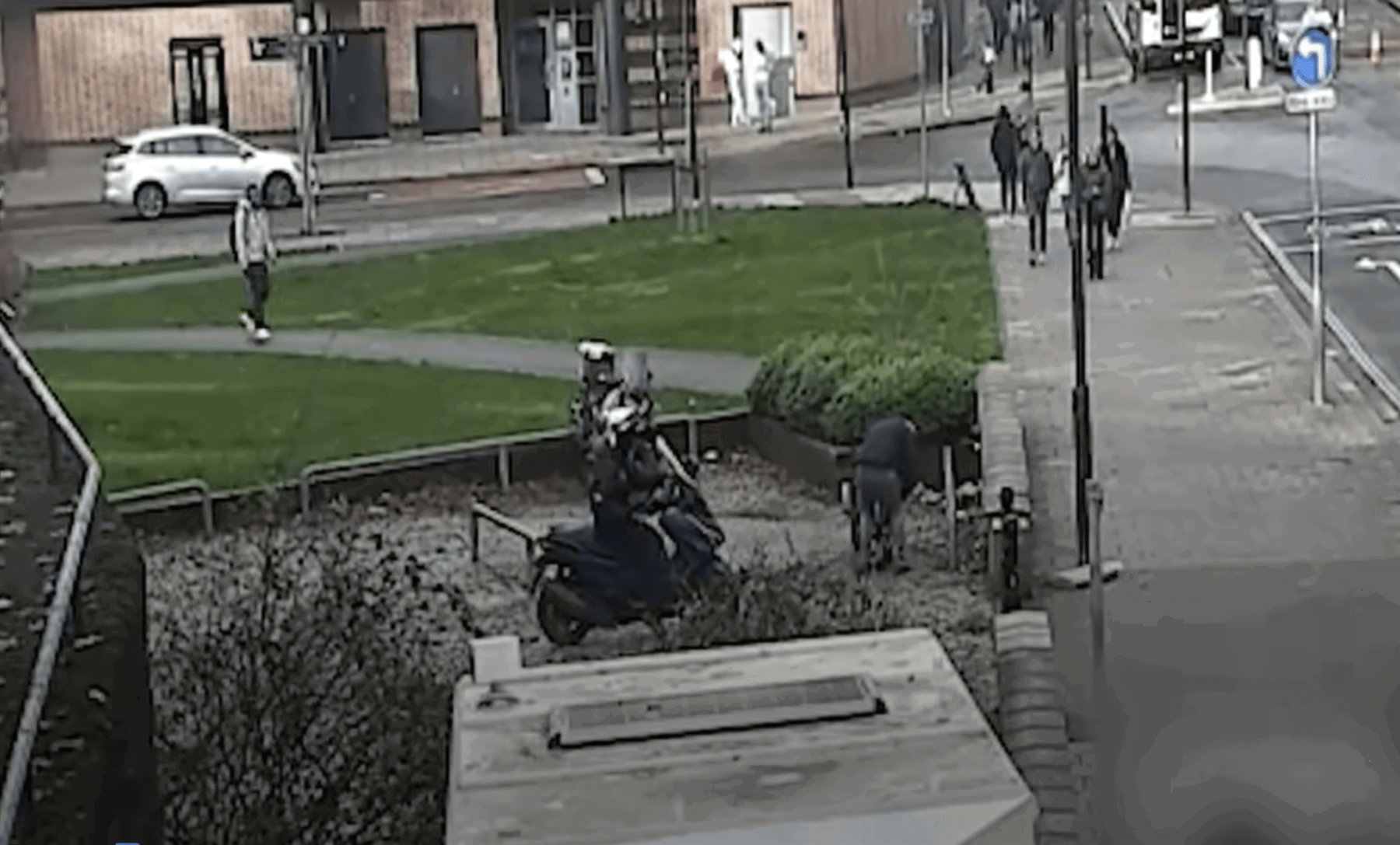 „The Repo Men“: Bristols Motorraddiebe prahlten sich ins Gefängnis 2 Körnige Überwachungskamera-Aufnahme von oben: ein abgestellter Motorroller auf einem Grünstreifen an einer Straßenkreuzung in Bristol, im Hintergrund Passanten und parkende Autos