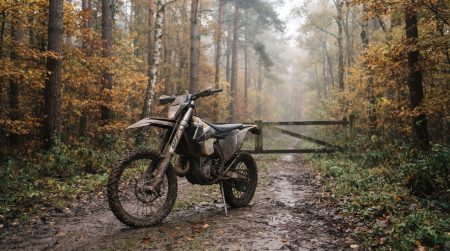 Verschlammtes Enduro-Motorrad steht einsam auf einem nebligen Waldweg im herbstlichen Mansfelder Land, im Hintergrund versperrt eine geschlossene Holzschranke den Weg – Symbolbild zur Absage der Motorradgeländefahrt 2026 (KI-generiert)