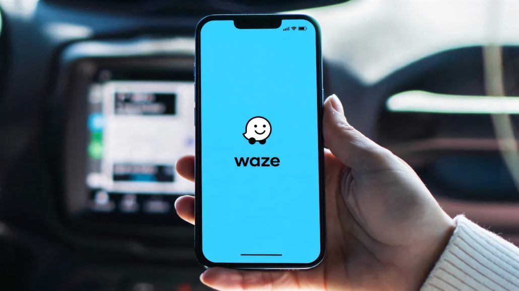 Waze startet KI-Motorradmodus: Deutschland muss noch warten 7 Waze Motorradmodus 2026 - Hand haelt Smartphone mit Waze-Startbildschirm im Auto vor unscharfem Armaturenbrett