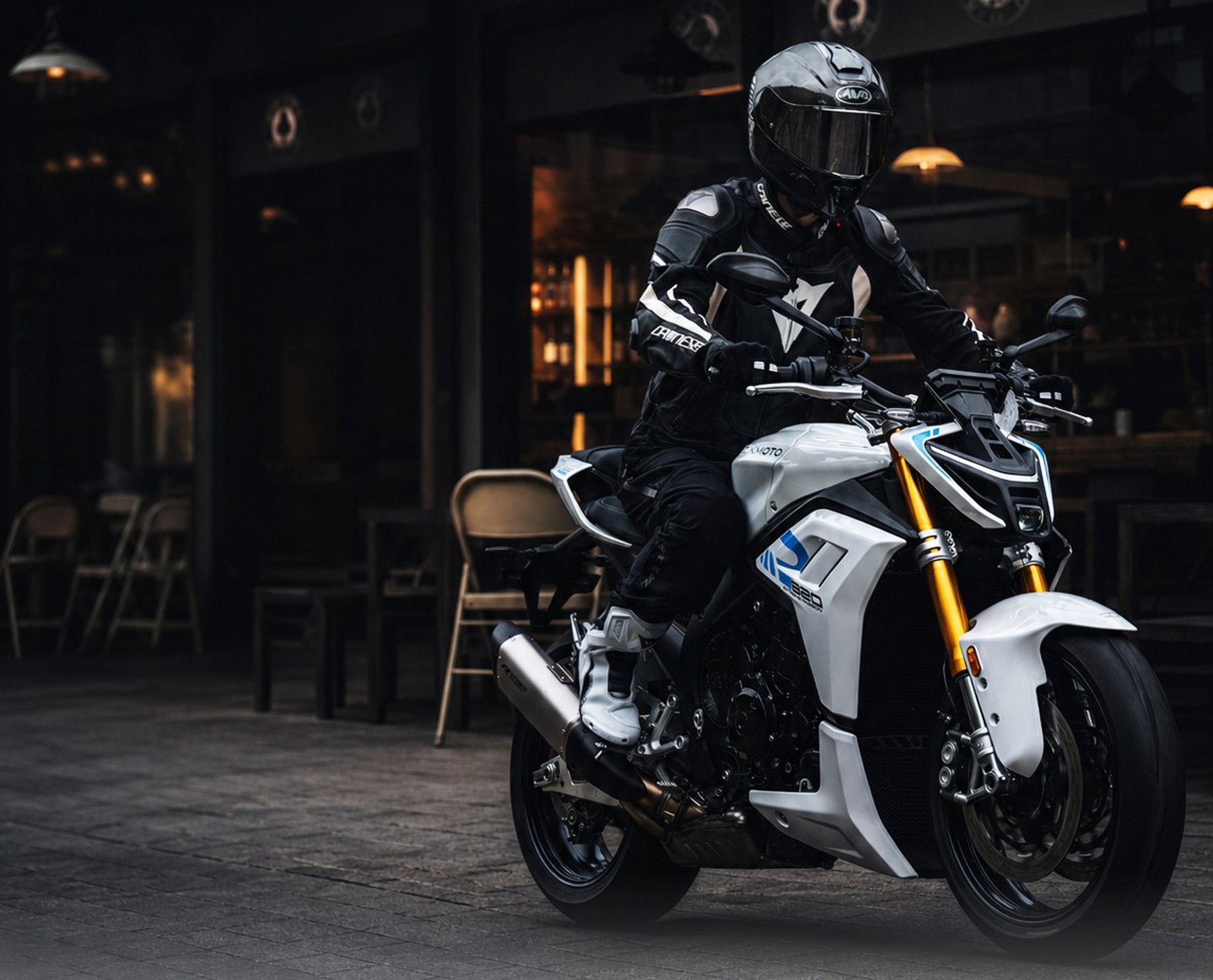 ZXMoto 820RR-R und 820R: WorldSSP-Sieger bringt seine Serien-Sportler 6 ZXMoto 820R 2026 - Fahrer auf weissem Naked Bike mit goldenen Upside-Down-Gabeln vor beleuchteter Bar-Fassade in der Daemmerung