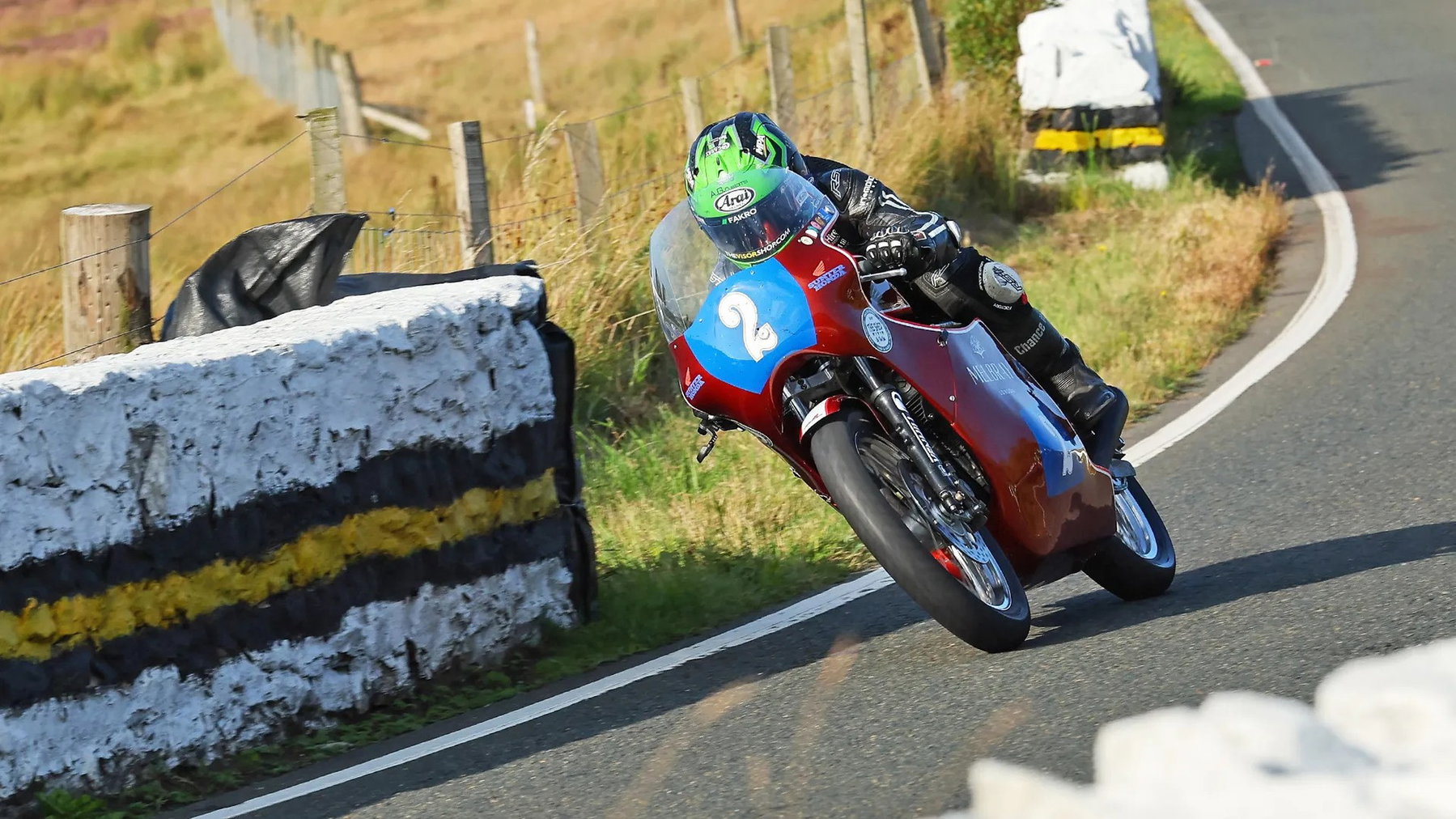 Michael Browne auf der rot-blauen Melbray-Racing-Honda mit der Startnummer 2 und steigendem Vorderrad im Bergabschnitt des Mountain Course – Historic Junior Classic TT, Isle of Man 2026