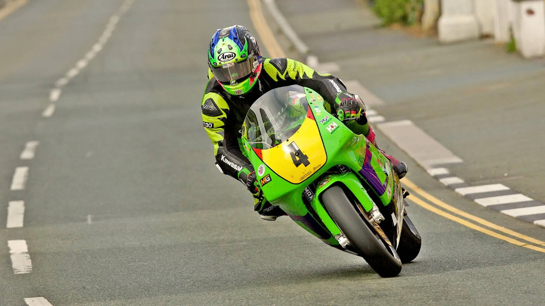 Jamie Coward auf der grünen Greenall Racing Kawasaki ZXR750 mit Startnummer 4 in Schräglage zwischen Häusern – Senior Classic TT, Isle of Man 2026