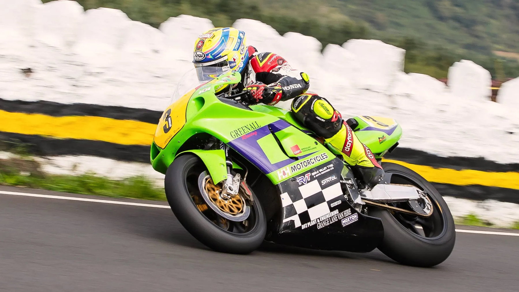 Nathan Harrison auf der grün-violetten Greenall Racing Kawasaki ZXR750 mit Startnummer 3 in Schräglage vor weißer Mauer – Senior Classic TT, Isle of Man 2026