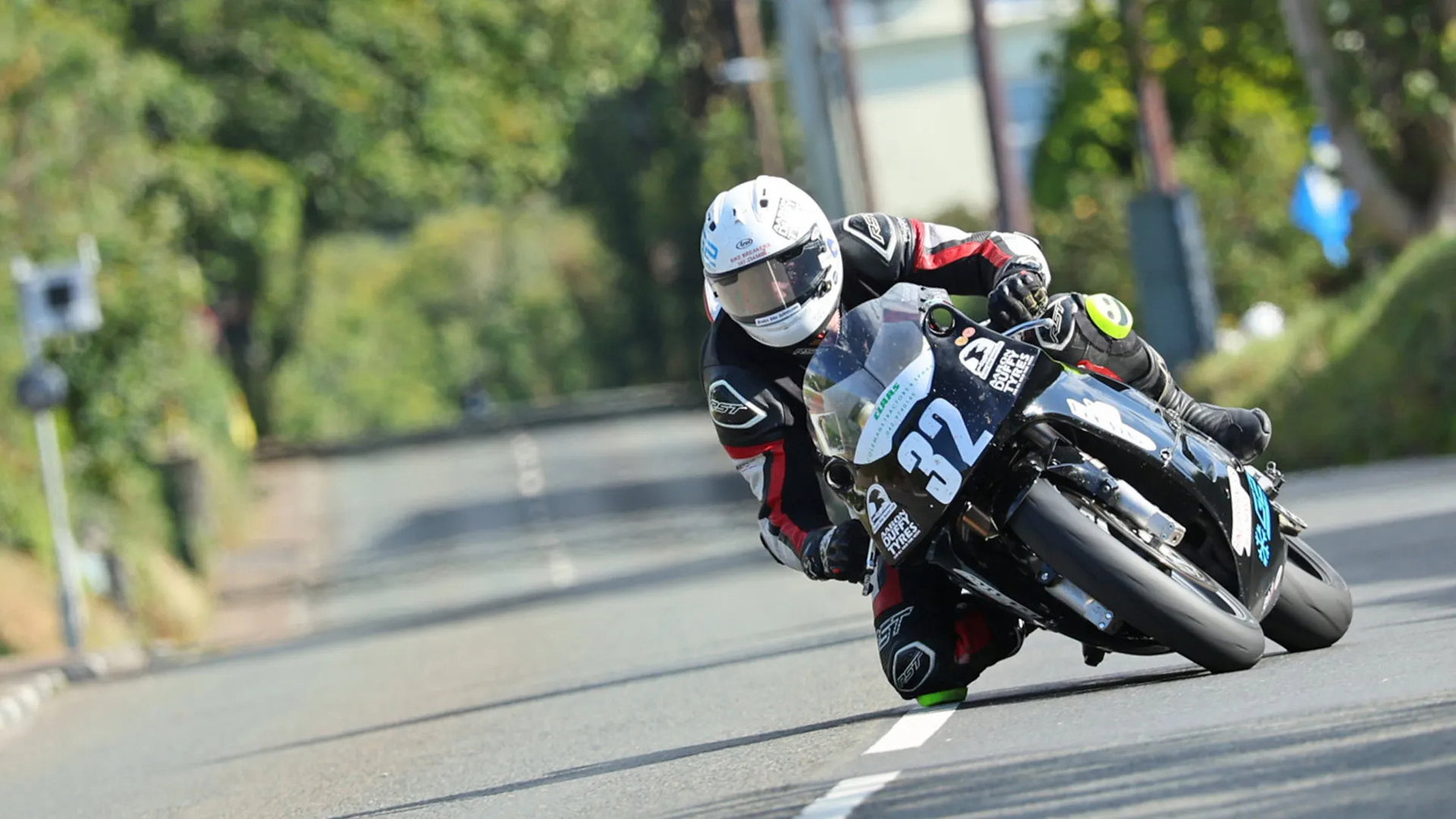 Classic TT: Dunlop Breaks the Anstey Record and Wins Twice in a Day 3 Joe Loughlin in tiefer Schräglage auf der schwarzen G2-Technical-Services-Kawasaki mit der Startnummer 32 auf einer von Hecken gesäumten Landstraße – Ultra-Lightweight Classic TT, Isle of Man 2026