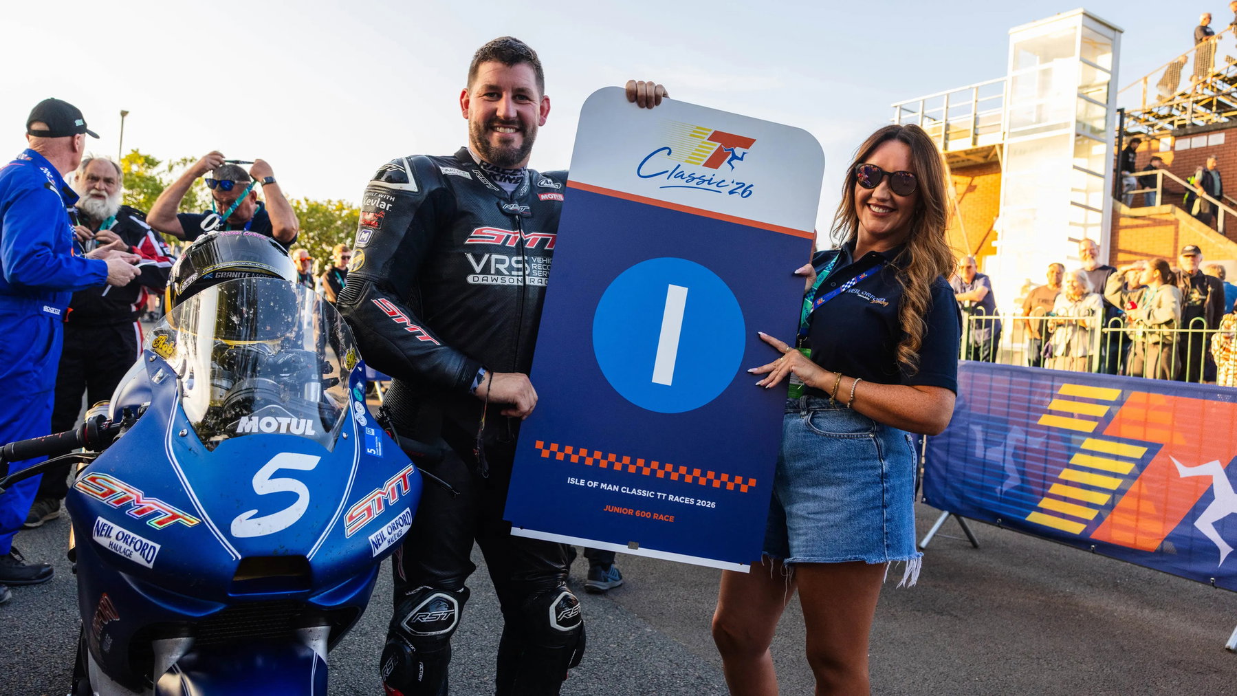 Rob Hodson wins the first Junior 600 Classic TT: Furber survives a fuel scare 1 Rob Hodson hält neben seiner blauen SMT-600er mit Startnummer 5 die Siegertafel des Junior 600 Race – Classic TT 2026, Isle of Man