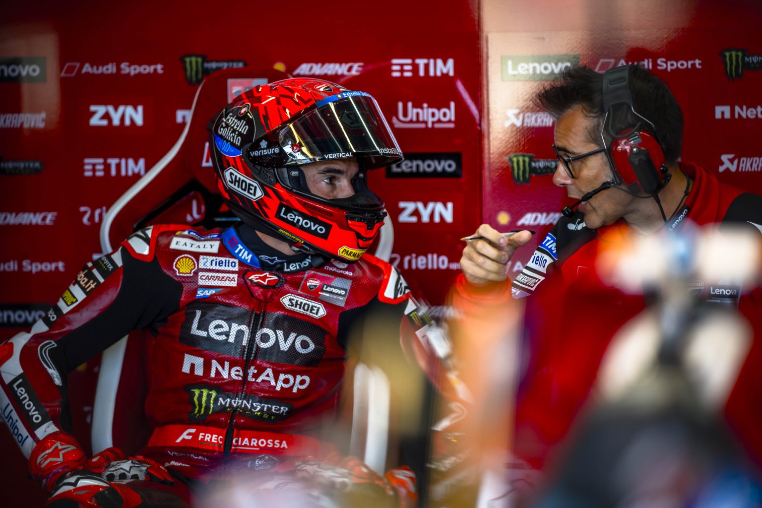 Marc Marquez im Helm im Gespräch mit seinem Techniker in der Box des Ducati Lenovo Teams – MotoGP Großbritannien GP Silverstone 2026