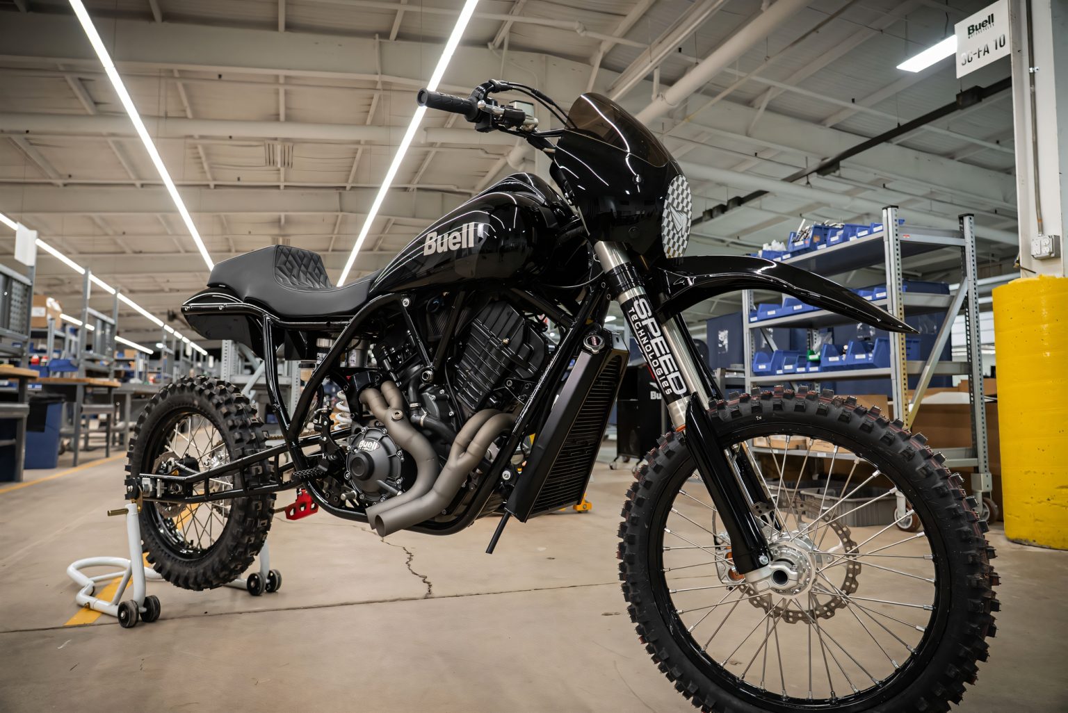 Buell The Goat: Bergrenn-Konzept könnte erstes Adventure-Modell werden Buell The Goat Bergrenn-Konzept 2026 – Halbseitliche Frontansicht des schwarzen Umbaus auf Basis der Super Cruiser, mit Stollenreifen, langhubiger WP-Gabel und getönter Scheibe in der Werkshalle von Buell.