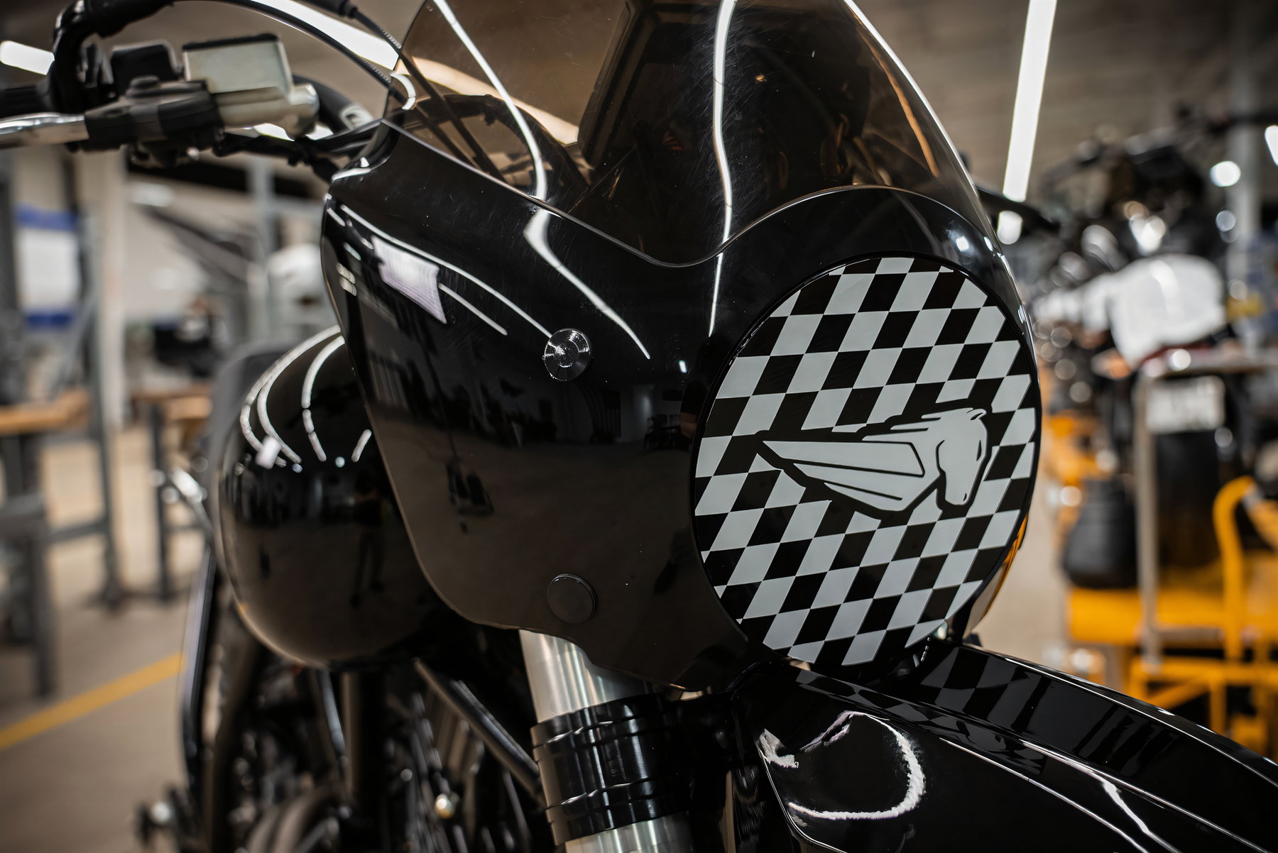 Buell The Goat Bergrenn-Konzept 2026 – Nahaufnahme der Frontverkleidung mit getönter Scheibe und rundem Schwarz-Weiß-Karo-Aufkleber mit stilisiertem Buell-Pegasus-Logo.