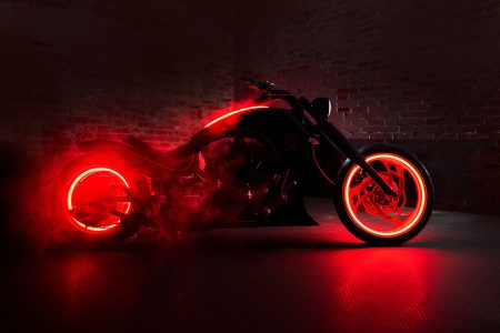 Dark Rider Custombike von Bourget's Bike Works in dramatischer Studioinszenierung mit rotem Rauch und Neonlicht, Seitenansicht vor dunkler Ziegelwand
