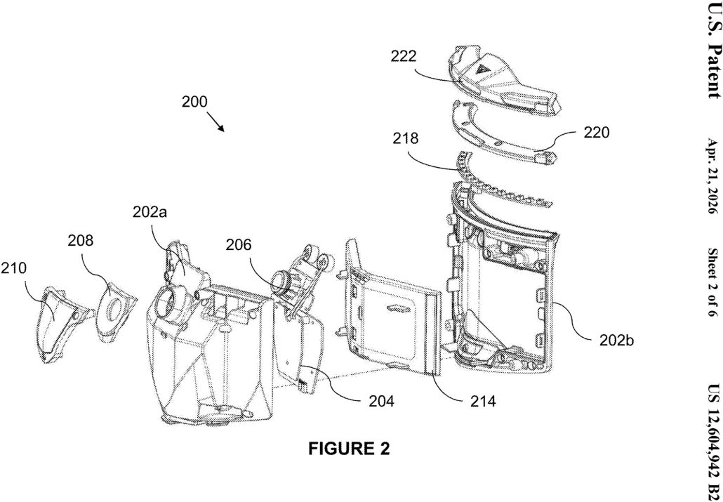 Technische Explosionszeichnung (FIGURE 2) aus der US-Patentschrift 12.604.942 B2: Einzelteile des Kinnbuegelmoduls eines Motorradhelms, darunter Frontblende mit Kameraobjektiv, Dichtung, Hauptplatine, Akkugehaeuse und rueckwaertiges Gehaeuseteil. Bauteil, nicht Totwinkelwarnung.