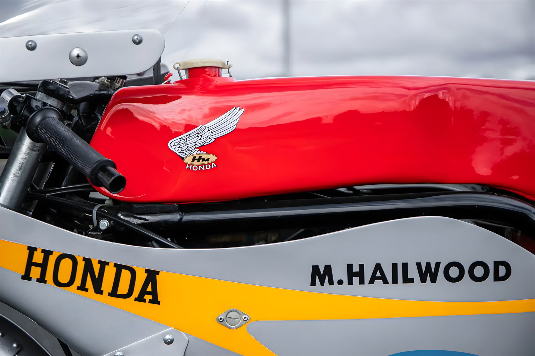 Hailwoods Honda RC173 kommt unter den Hammer: Rekordpreis in Sichtweite 1 Detailaufnahme des roten Tanks der Honda RC173 mit weißem Honda-Fluegellogo, HM-Honda-Schriftzug und silbergrauer Verkleidung mit M.Hailwood-Beschriftung