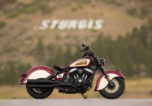 Rechte Seitenansicht in Indian Motorcycle Red und Cream vor dem weißen STURGIS-Schriftzug am Berghang in South Dakota