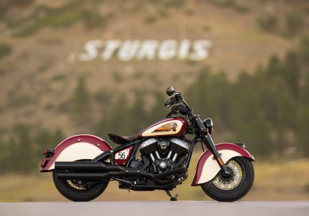Rechte Seitenansicht in Indian Motorcycle Red und Cream vor dem weißen STURGIS-Schriftzug am Berghang in South Dakota