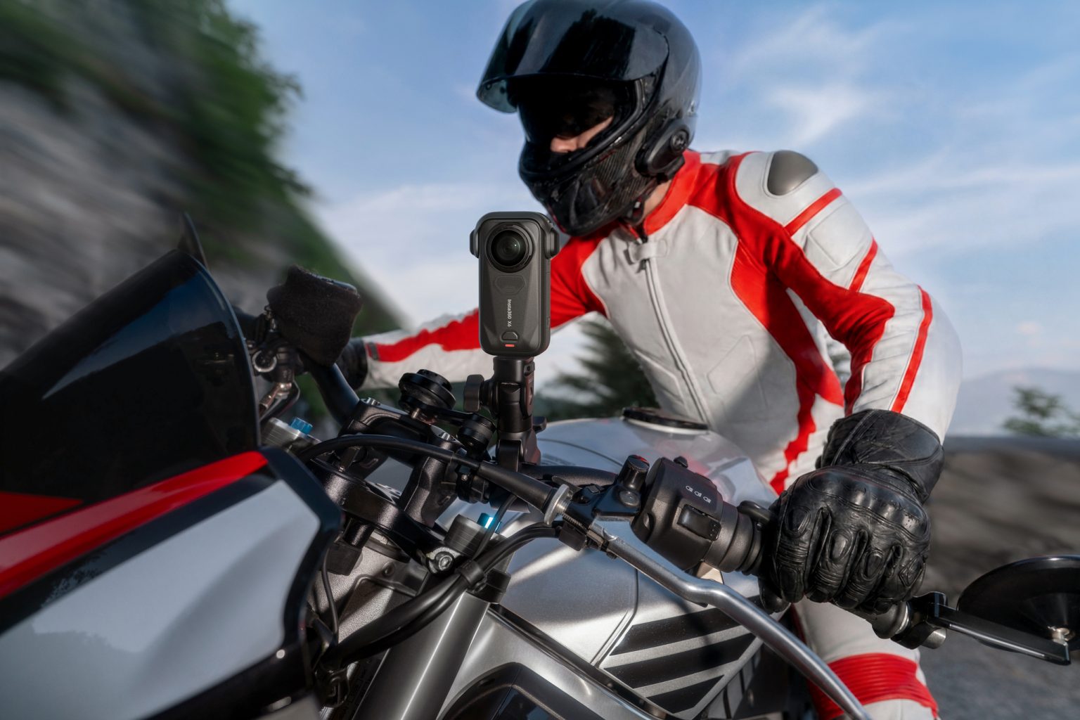 Insta360 X6 ab 699 Euro: Was die 8K-Kamera Motorradfahrern bringt Insta360 X6 – am Motorradlenker montiert, Fahrer in rot-weißer Lederkombi mit schwarzem Integralhelm in Fahrt