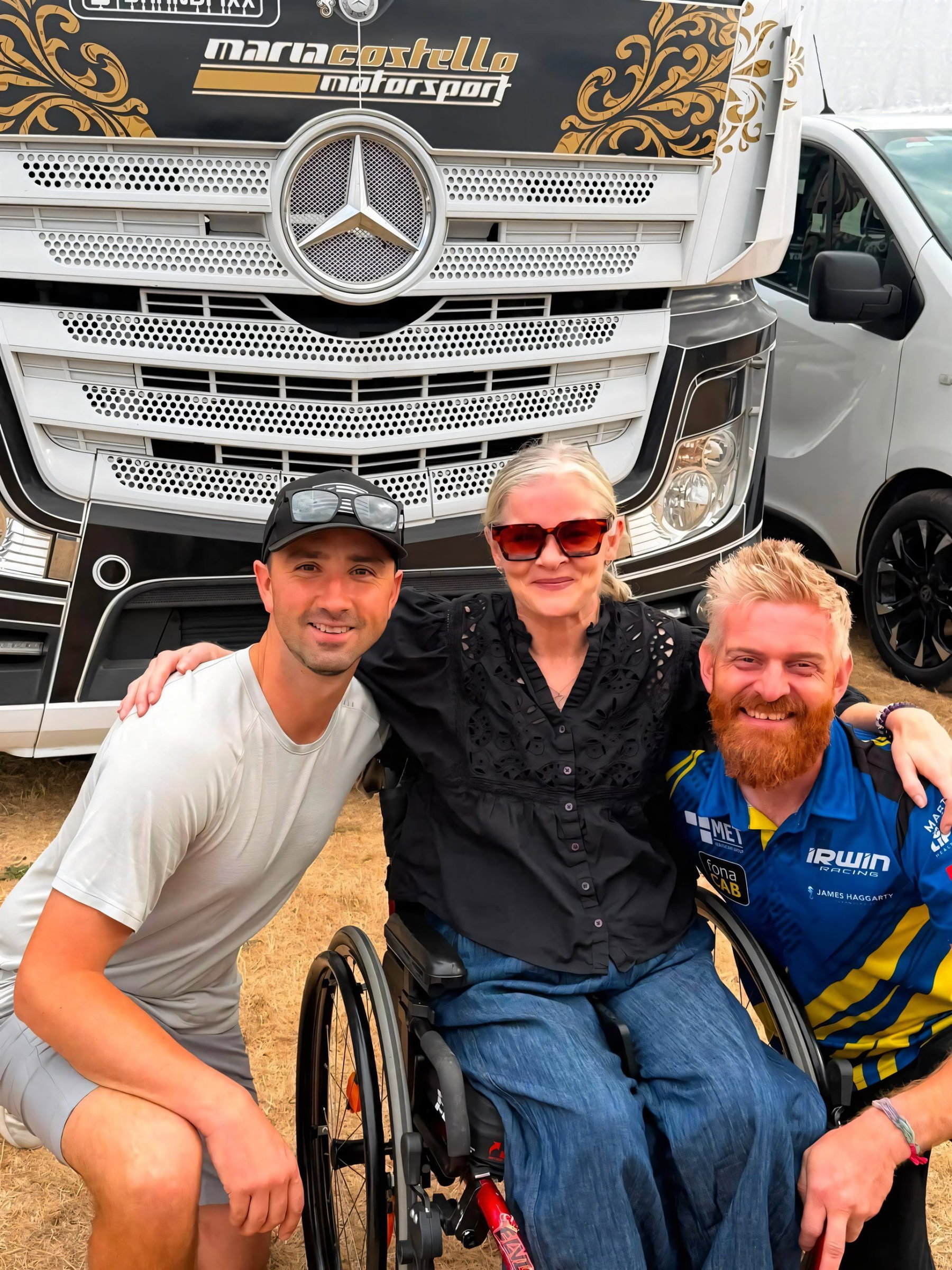 Maria Costello zurück im Fahrerlager: Was der Besuch in Thruxton bedeutet 5 Maria Costello im Rollstuhl beim Gruppenfoto mit zwei Fahrern vor dem Mercedes-Actros-Truck von Maria Costello Motorsport im Fahrerlager von Thruxton