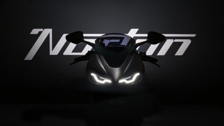 Norton Manx R (2026) – Frontansicht im abgedunkelten Studio mit beleuchtetem Norton-Schriftzug und LED-Scheinwerfern