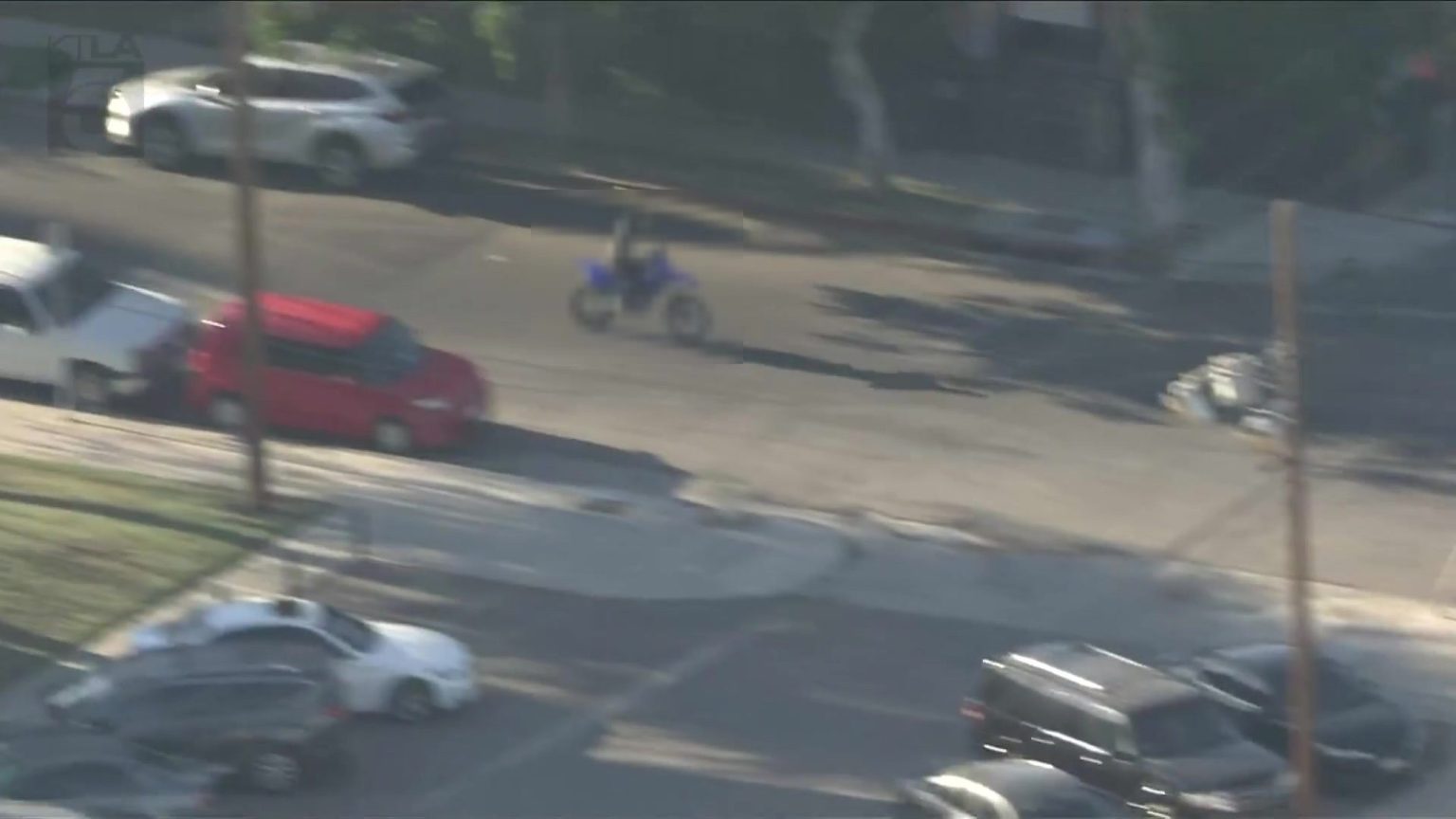Dirtbike-Verfolgungsjagd in Los Angeles: Am Ende fehlte die Waffe Luftaufnahme eines Dirtbike-Fahrers, der bei einer Polizeiverfolgungsjagd in Los Angeles zwischen Autos über eine breite Kreuzung fährt, die Person ist durch Verpixelung unkenntlich gemacht