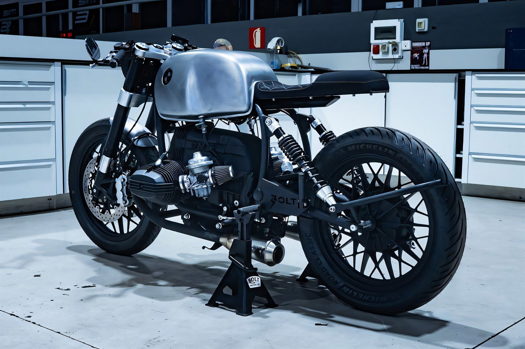 BMW R 100 aus der Holzkiste: Bolt Motor baut den Boxer komplett neu 1 BMW R 100 Umbau von Bolt Motor Company, Heckansicht schraeg von hinten mit Boxermotor, offenem Ansaugtrichter, Auspuff und Montagestaender mit Bolt-Motor-Co-Logo