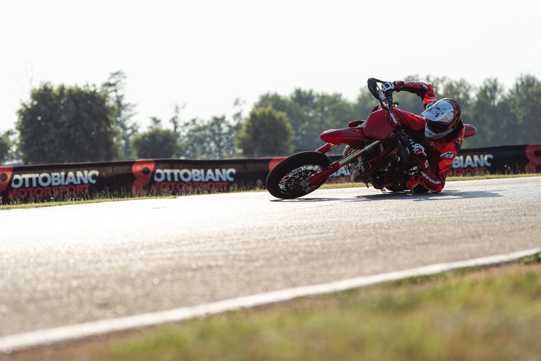 Ducati Desmo450 SM 2027 – Supermoto-Fahrer in tiefer Schräglage auf der Rennstrecke vor Werbebanden