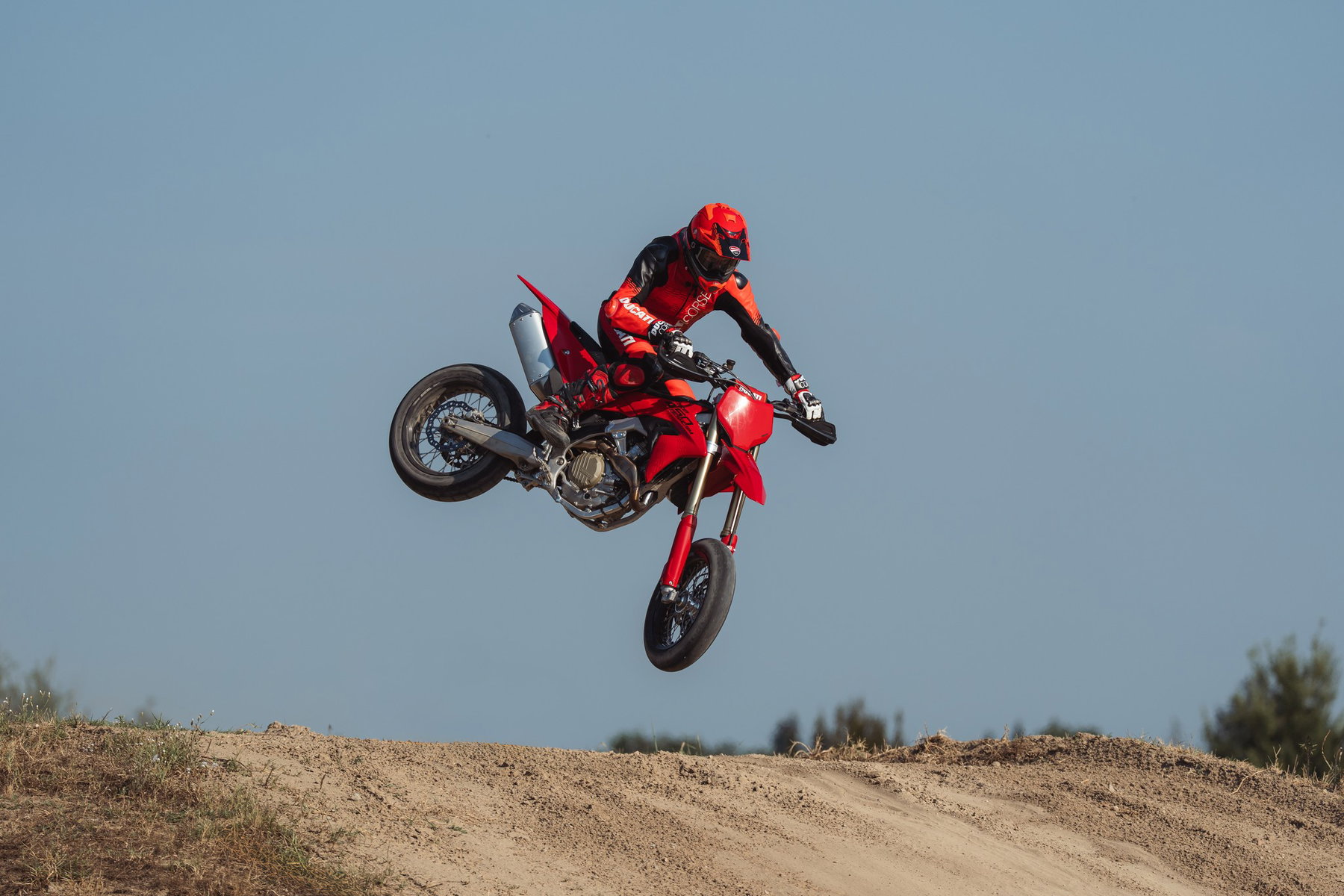 Ducati Desmo450 SM 2027 – Sprung über einen Erdhügel vor blauem Himmel