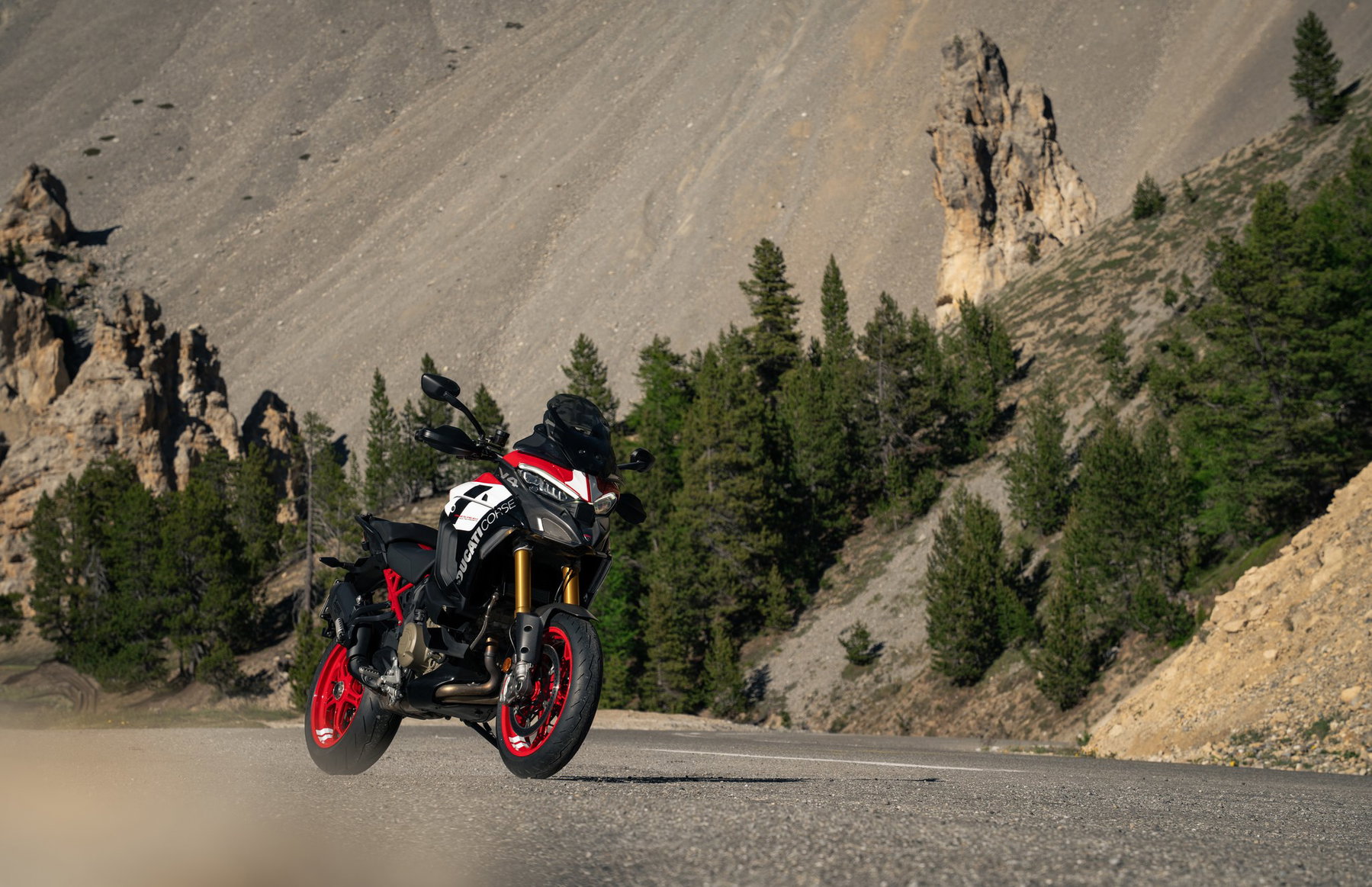 Ducati Multistrada V4 Pikes Peak 2027: MotoGP Look, Same Technology 1 Ducati Multistrada V4 Pikes Peak 2027 mit Ducati-Corse-Schriftzug und Startnummer 1 auf der Verkleidung, schräg von vorn links auf einer Bergstraße mit Felsen und Kiefern