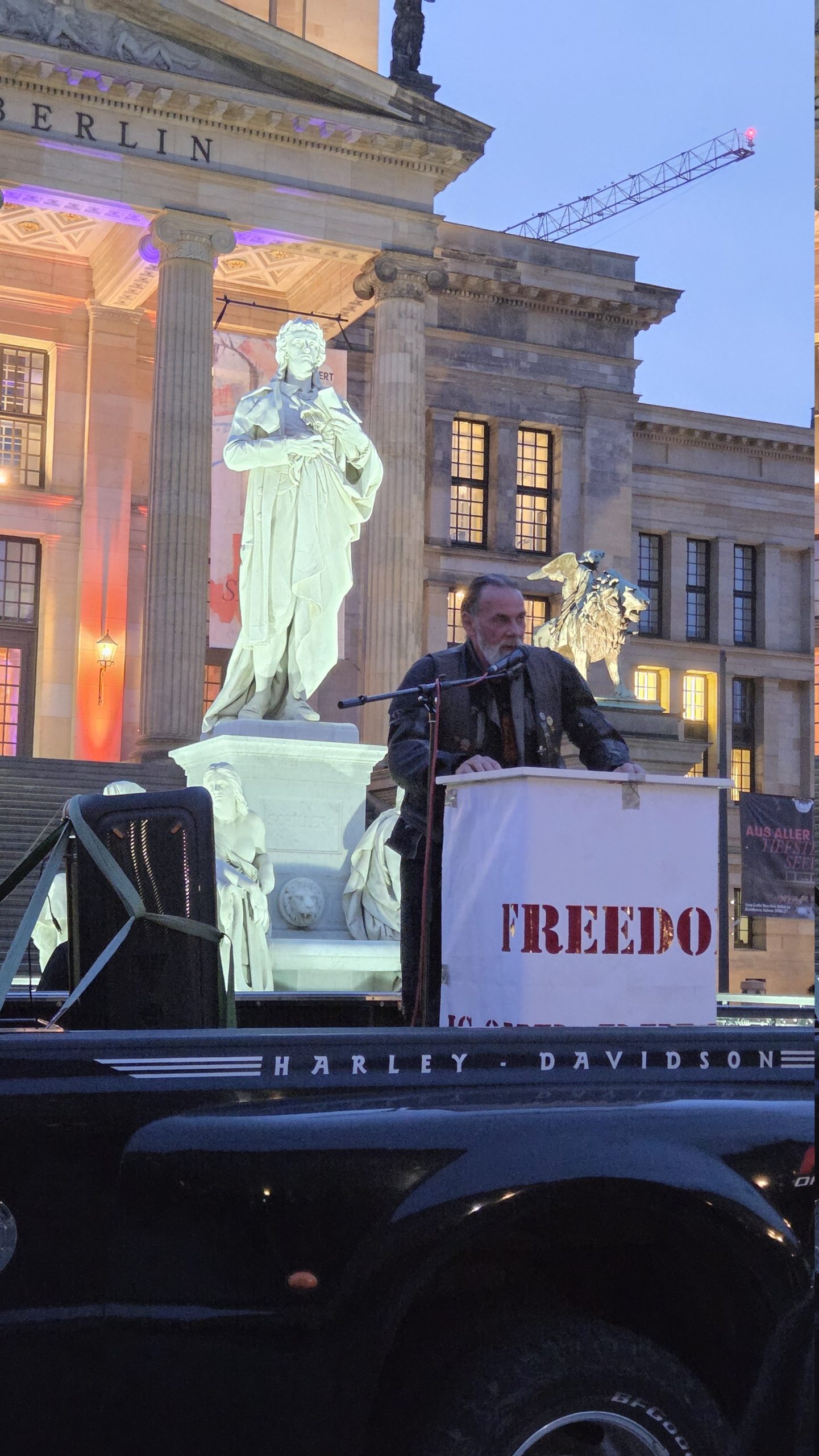Freedom is our Religion: 700 Biker und der Streit ums Polizeigesetz 3 Redner am Mikrofon hinter einem Freedom-is-our-Religion-Pult auf der mobilen Bühne vor dem Schiller-Denkmal und dem Konzerthaus Berlin