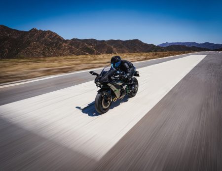 Kawasaki Ninja H2 2027 – Fahraufnahme von schräg vorne auf einer Rollbahn vor Bergkulisse unter blauem Himmel