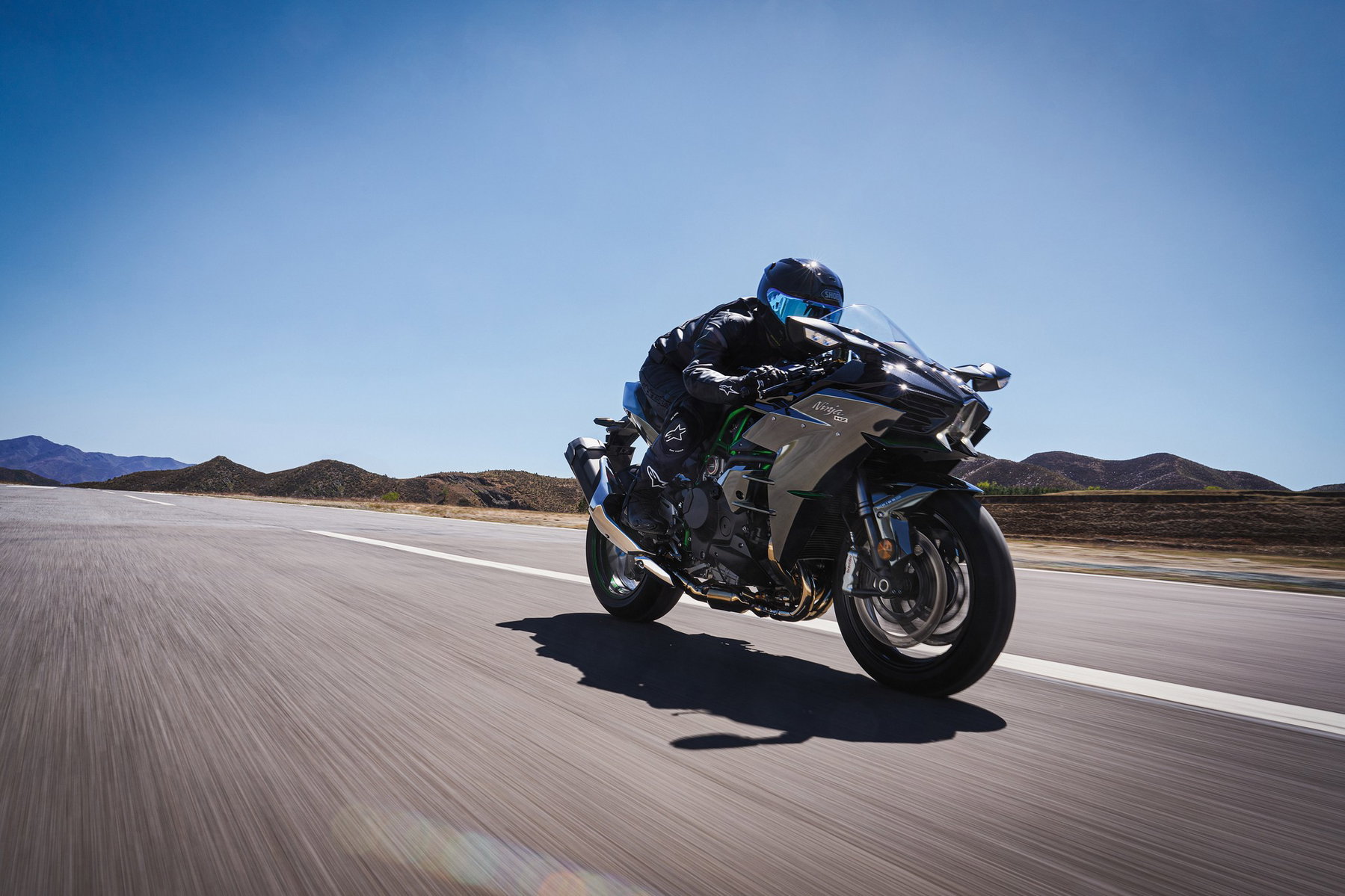 Kawasaki Ninja H2 returns: How much H2 SX is in the new engine 5 Kawasaki Ninja H2 2027 – Fahrer in Schräglage auf Asphaltpiste mit Wüstenbergen im Hintergrund