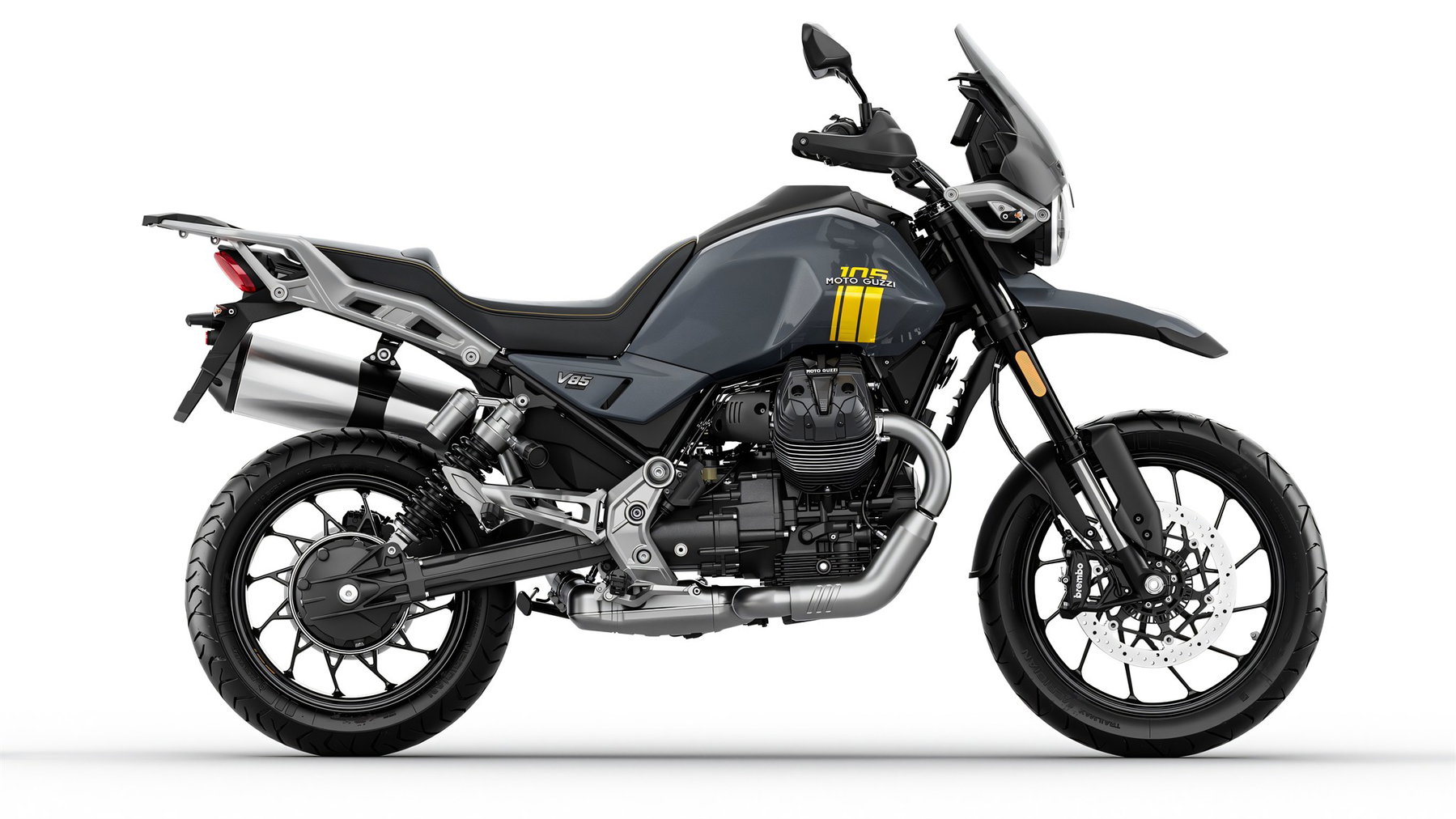 Moto Guzzi 105th Anniversary Edition: Fünf Modelle tragen die Farben des neuen Werks 5 Moto Guzzi V85 Strada 105th Anniversary Edition – Seitenansicht in Perlglanz-Grau mit gelber 105-Jubiläumsgrafik am Tank und Speichenrädern, Studioaufnahme vor weißem Hintergrund