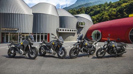 Vier Moto-Guzzi-Sondermodelle der 105th Anniversary Edition vor dem neu gestalteten Werksgelände mit Museum in Mandello del Lario, im Hintergrund die Berge am Comer See