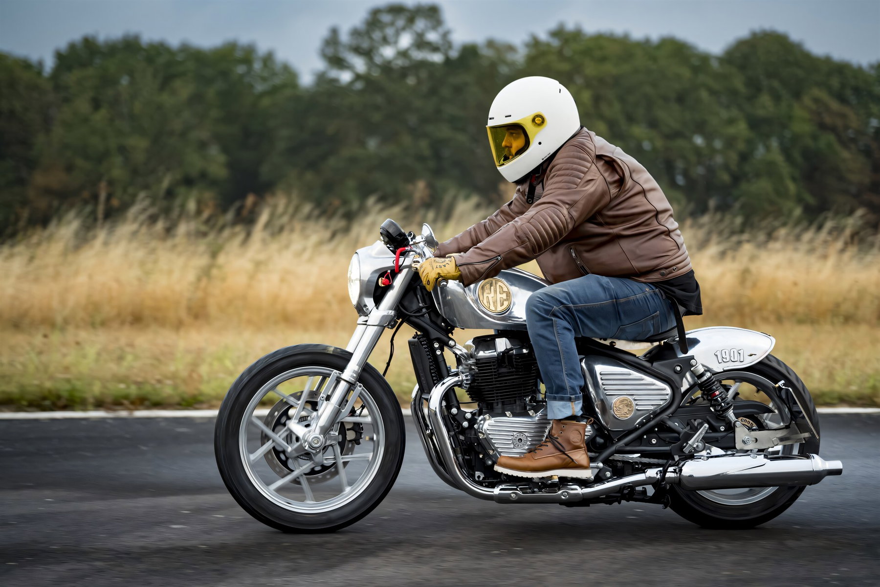 Royal Enfield Parivar: Shotgun 650 Custombike verlost 5 Royal Enfield Parivar 2026 – Fahraufnahme auf einer Landstraße, Fahrer in brauner Lederjacke mit weißem Helm