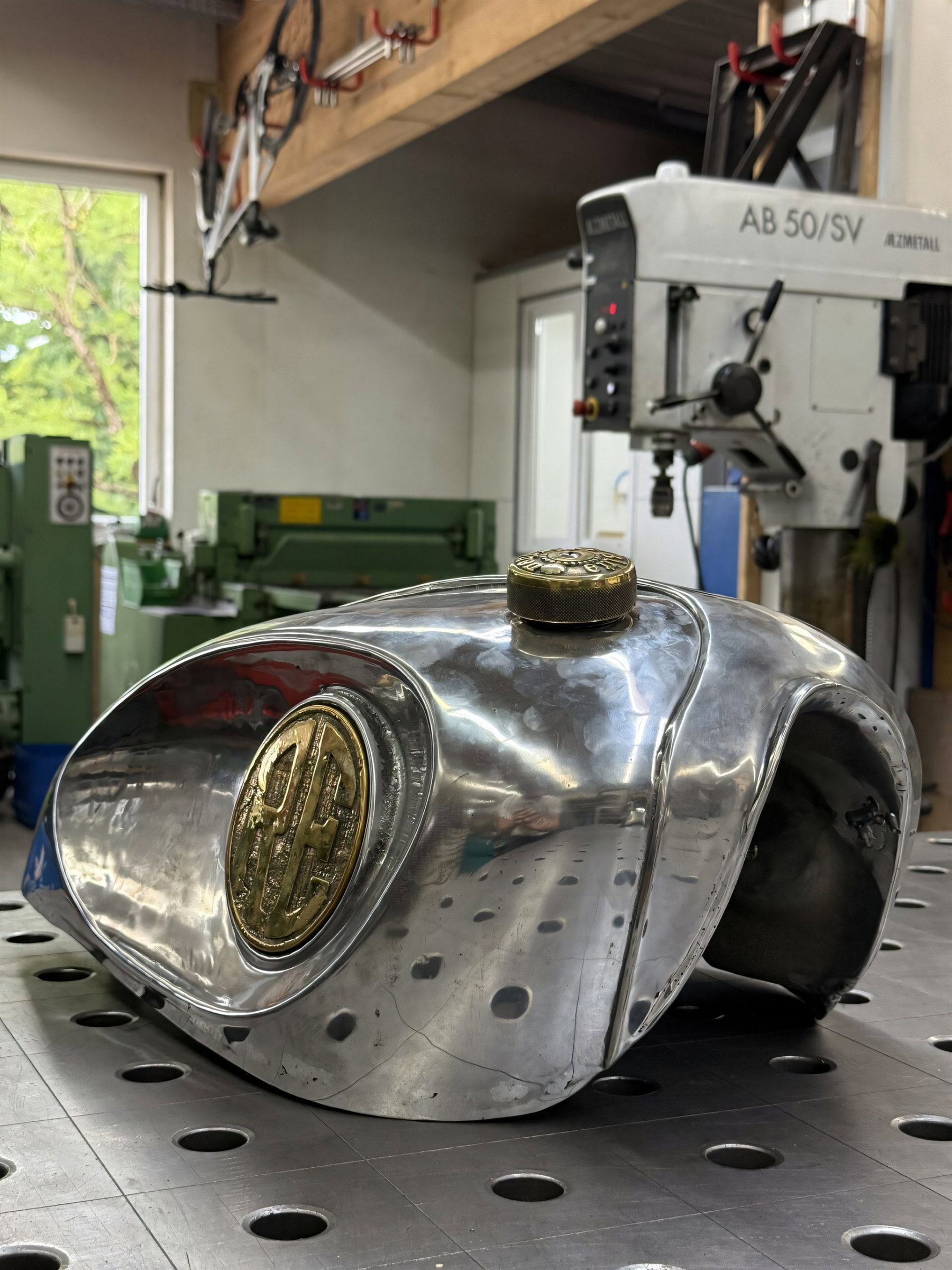 Royal Enfield Parivar: Shotgun 650 Custombike verlost 3 Fertig gegossener Aluminiumtank der Royal Enfield Parivar 2026 mit Messing-Medaillon und Messing-Tankdeckel auf dem Schweißtisch
