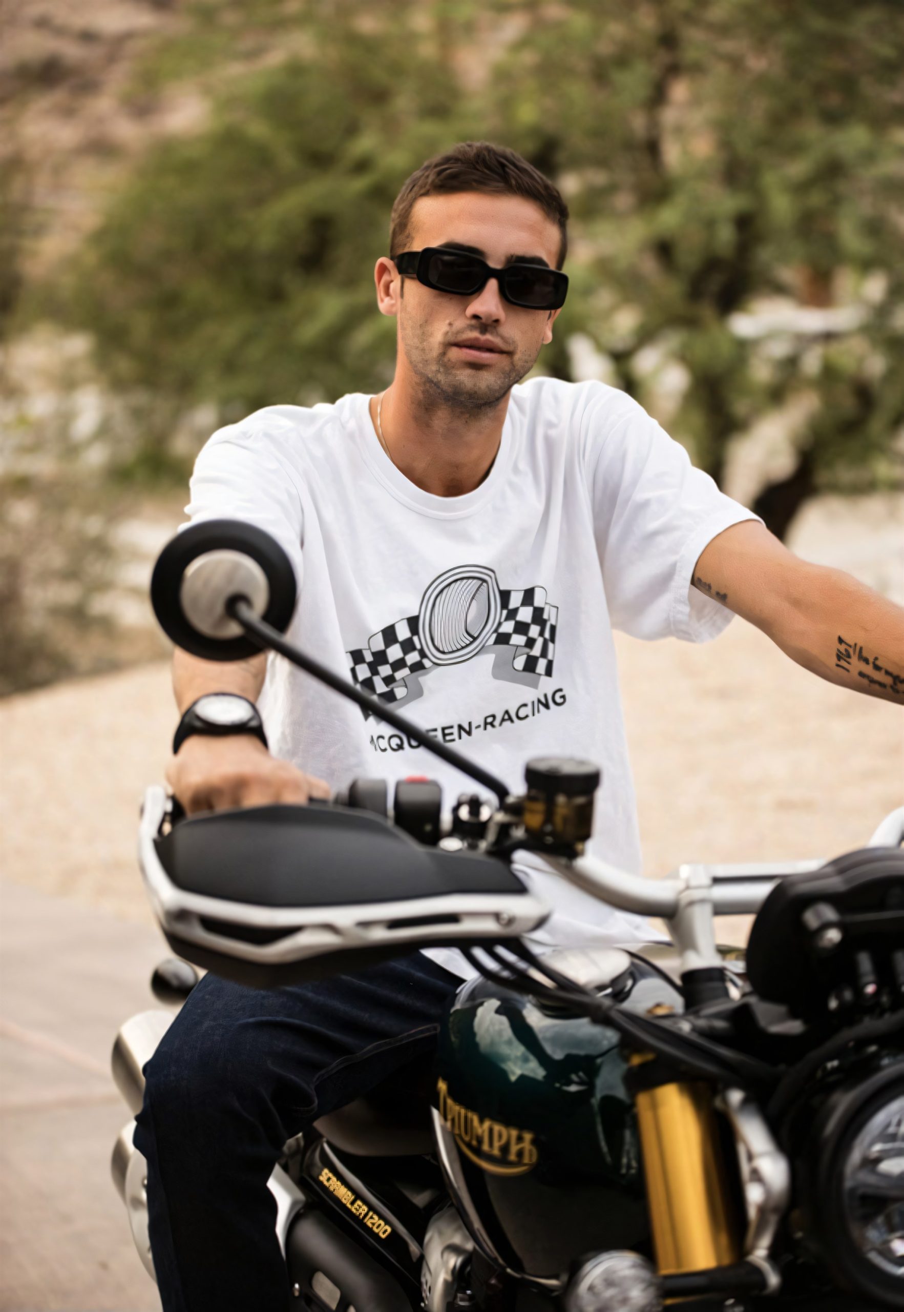 Triumph Originals 2026: Wie sieben Werkstätten die Scrambler neu denken 3 Chase McQueen im weißen McQueen-Racing-Shirt auf einer grünen Triumph Scrambler 1200 im Freien