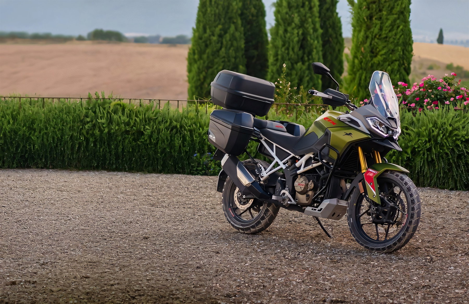 TVS RTX 300 2026 – Adventurer-Ausstattung mit schwarzem Topcase und Seitenkoffern vor toskanischer Kulisse mit Zypressen